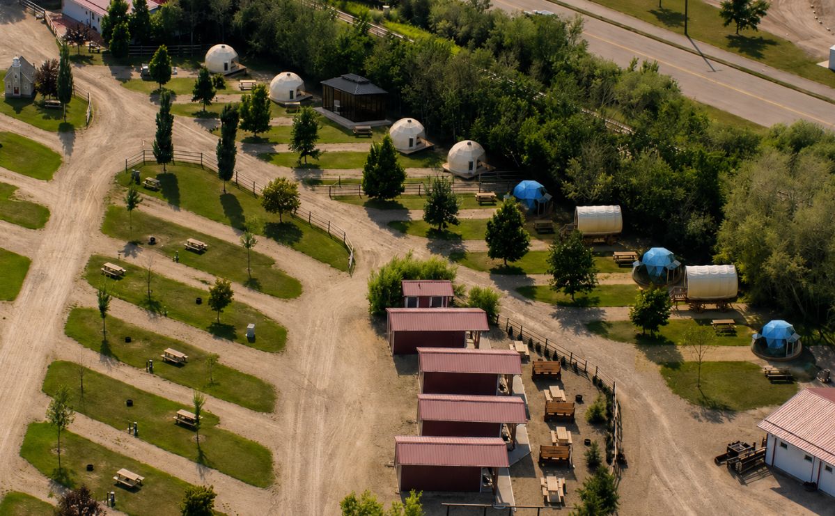 Aerial view of the Prairie Haven glamping village at Prairie Junction — geodesic domes and covered wagons in Stettler