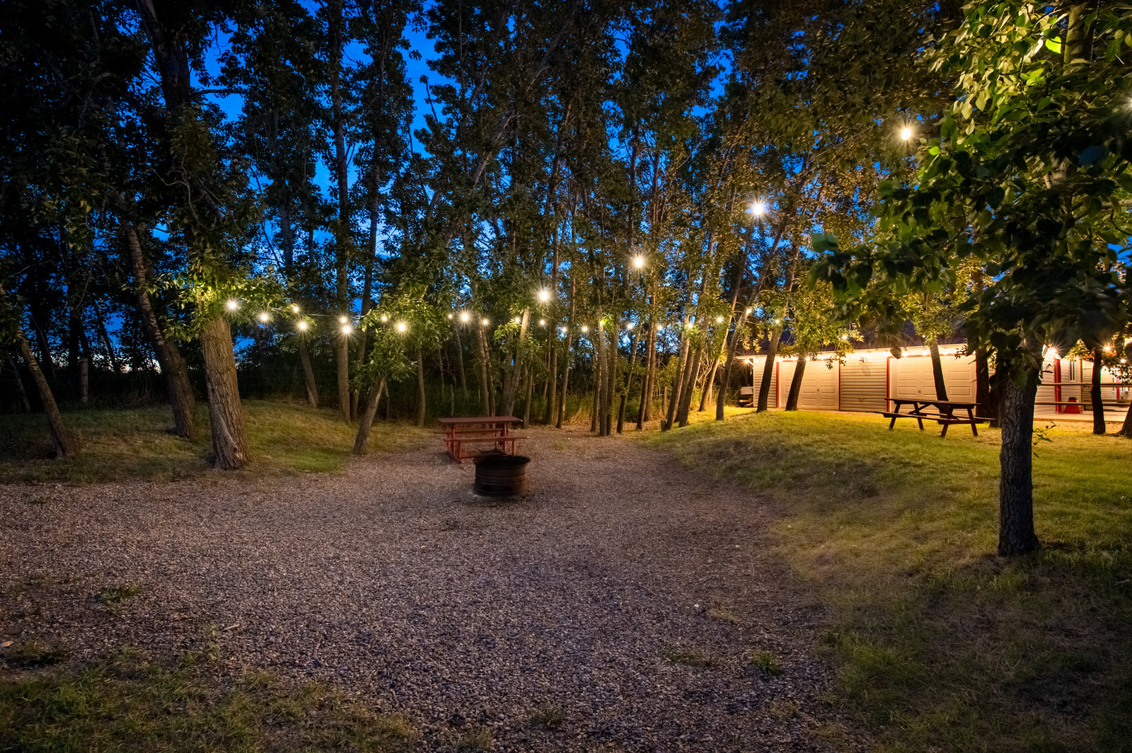 Evening around the fire pit in the group camping area, with the event centre lit up behind